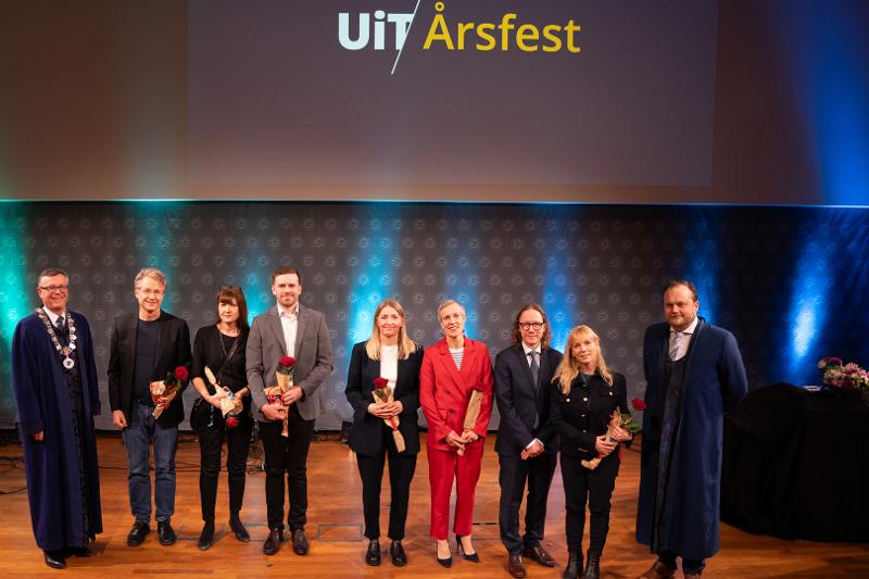 ei gruppe meddeske i pene klede framst i eit auditorium